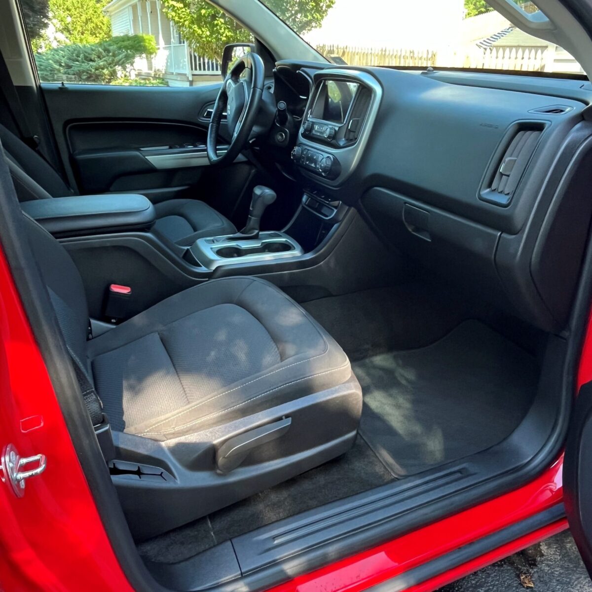 Interior of a red vehicle showing the driver's and front passenger seats, dashboard, steering wheel, and center console.